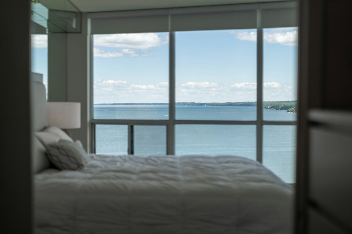 Bedroom with a large window overlooking a beautiful blue lake