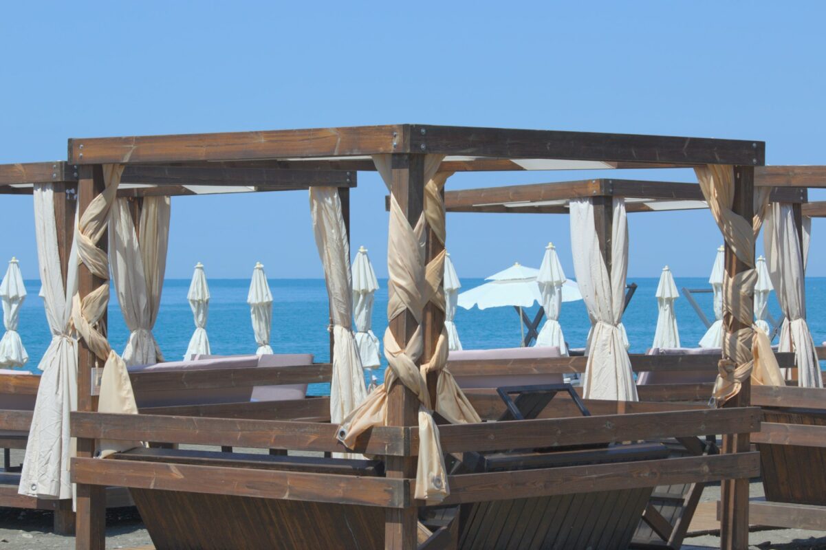 Beach cabanas with ocean and umbrellas in background